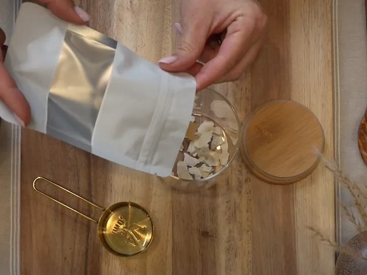 Dried starter flakes being tipped from the packet into a glass jar.